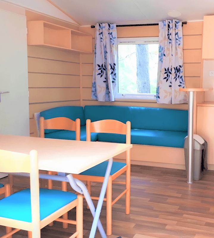 Banquette de mobil-home rénovée en simili-cuir bleu, avec rideaux imprimés
