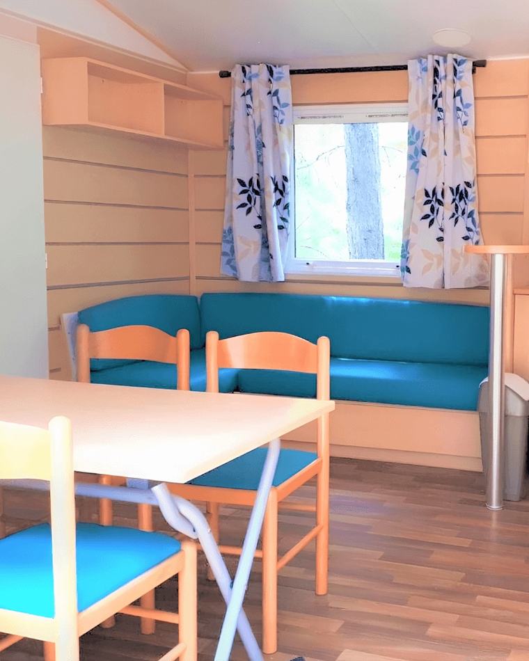 Mobil-home rénové par l’atelier : banquette en simili-cuir bleu et rideaux imprimés